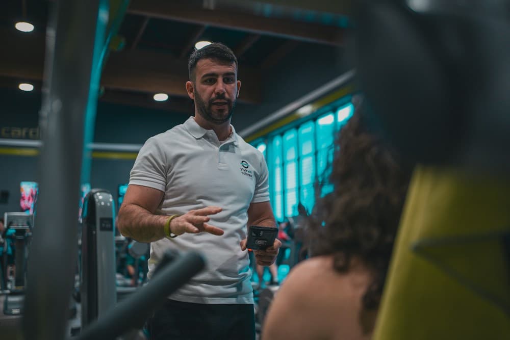 A fitness coach working with a member in a gym
